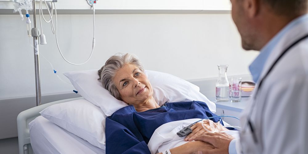 Ein Arzt spricht mit einer Patientin am Krankenbett über die Ursache ihrer Psychose.