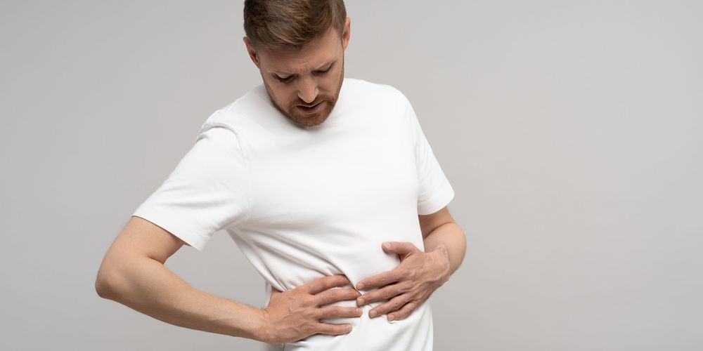 Was sind erste Anzeichen für Leberkrebs?  Ein Mann leidet unter Druckschmerz im Bauch, ein Symptom für Leberkebs.