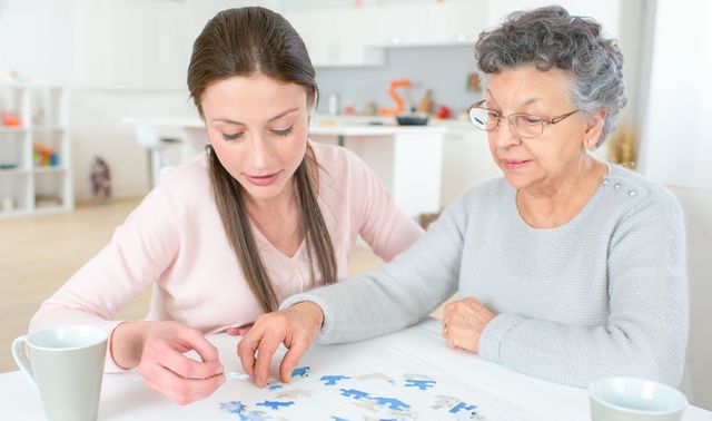 Die Grafik zeigt eine von Demenz betroffene Frau mit einer Angehörigen beim Trainieren des Gedächtnisses durch Puzzeln.