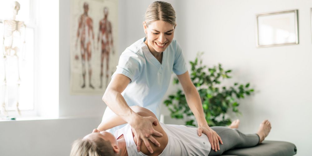 Eine Frau mit Rückenschmerzen probiert bei der Physiotherapie zunächst konservative Maßnahmen vor einer Spondylodese.