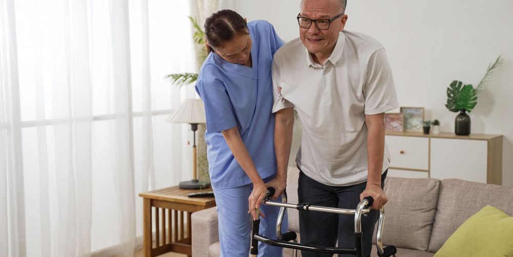 Eine Krankenpflegerin unterstützt einen Mann bei den Spätfolgen eines Schlaganfalls.