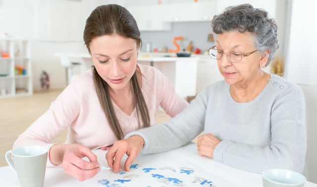 Die Grafik zeigt eine von Demenz betroffene Frau mit einer Angehörigen beim Trainieren des Gedächtnisses durch Puzzeln.