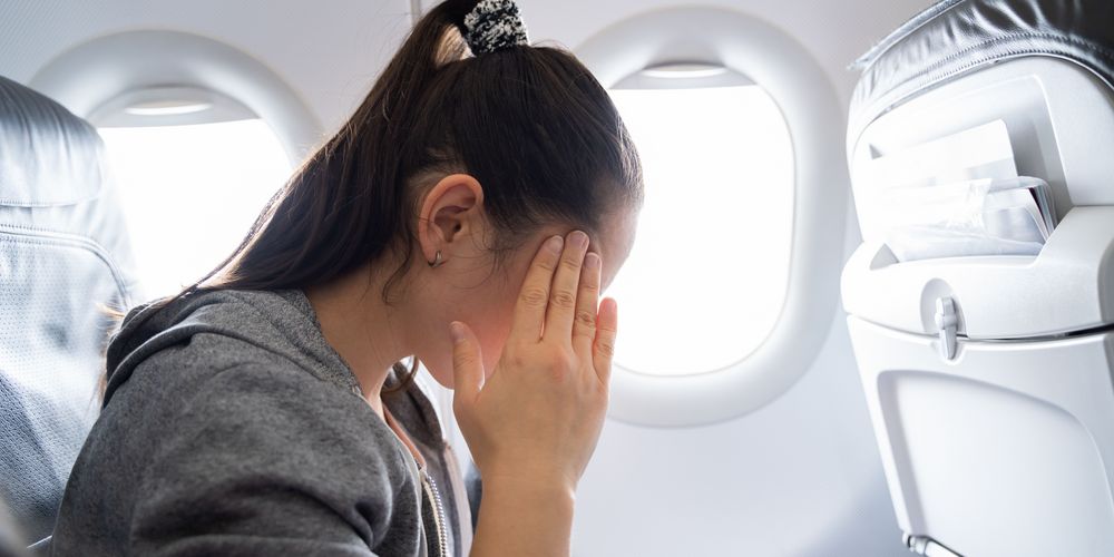 Eine Frau fühlt sich unwohl im Flugzeug, was eine Panikattacke auslösen kann.