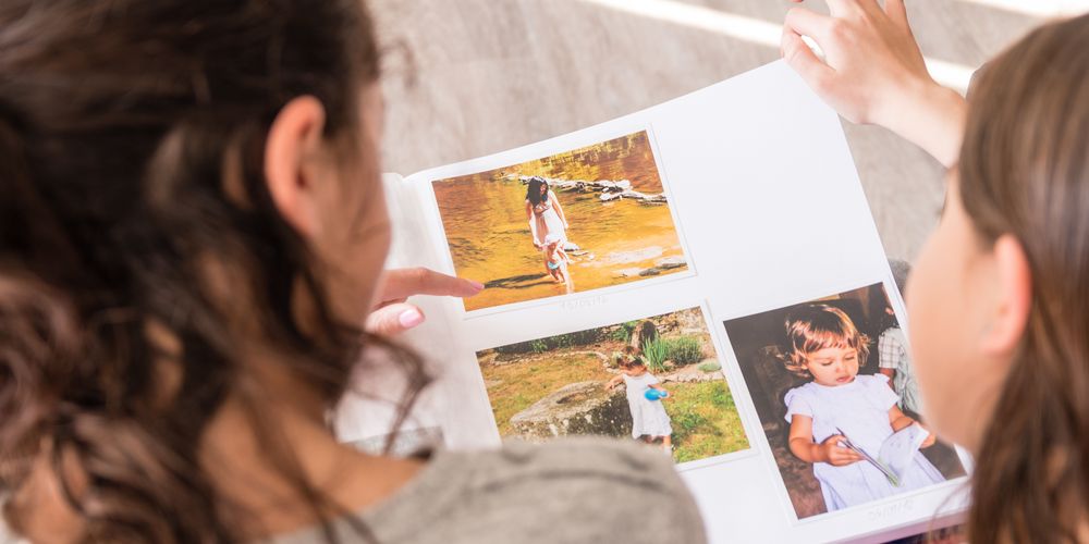 Eine Mutter schaut mit ihrer Tochter ein Fotoalbum an, um Ängste überwinden und verstehen zu können. 