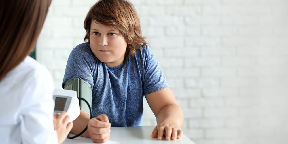 Eine Ärztin behandelt einen Jungen und erklärt ihm den Zusammenhang zwischen Übergewicht und Krebs.