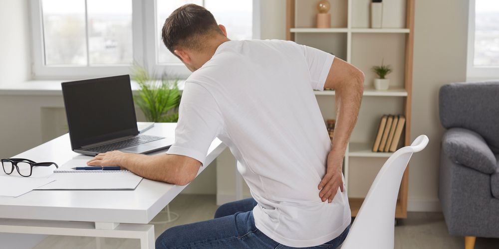 Ein Mann hat Rückenschmerzen als Anzeichen für Ischias aufgrund chronischer Fehlhaltung.