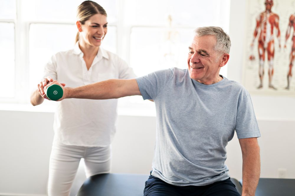 Eine Physiotherapeutin hilft einem älteren Patienten mit seiner Osteoporose.