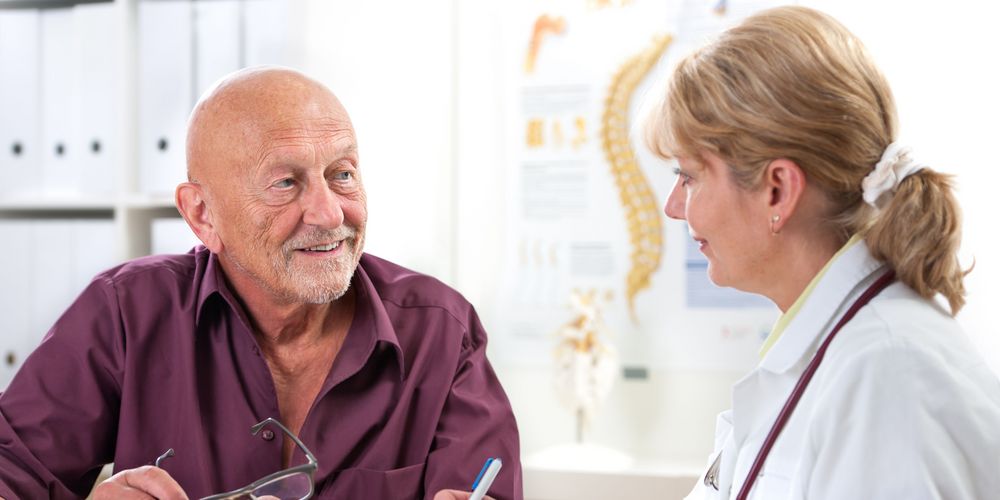 Eine Ärztin und einen Patienten, die Möglichkeiten zur Therapie einer Skoliose im Rücken besprechen.