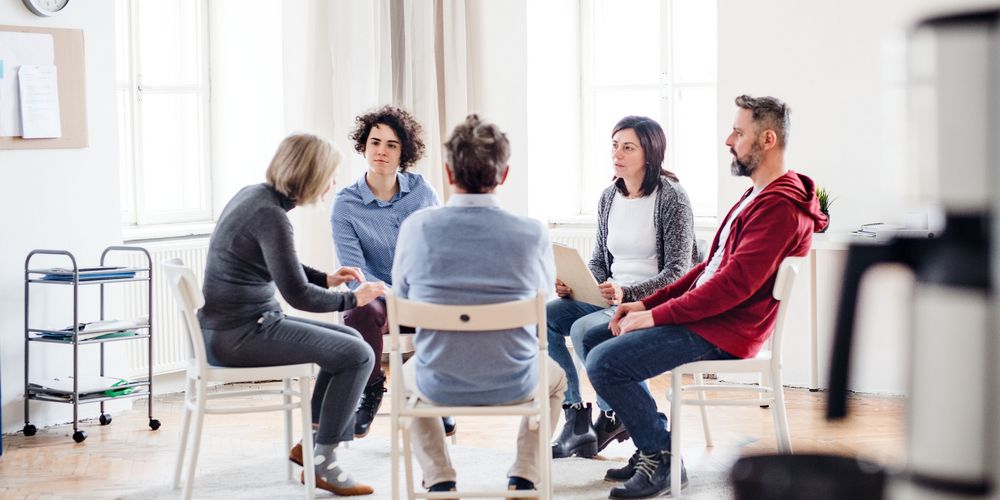 Man sieht eine Gruppe von Menschen, die zusammen an einer Gruppentherapie für ihre Borderline-Erkrankung teilnehmen.