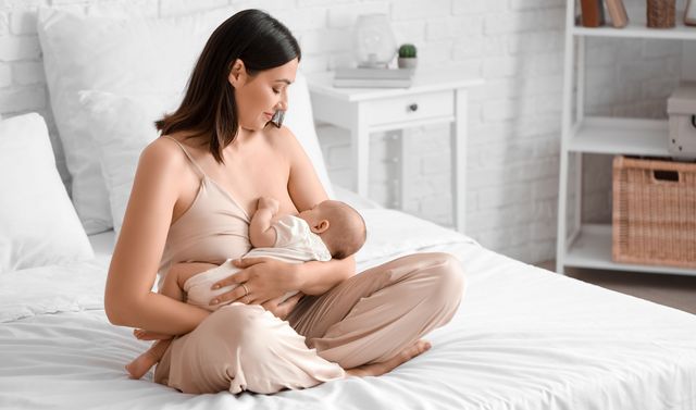 Eine Mutter stillt ihr Baby trotz Brustentzündung.