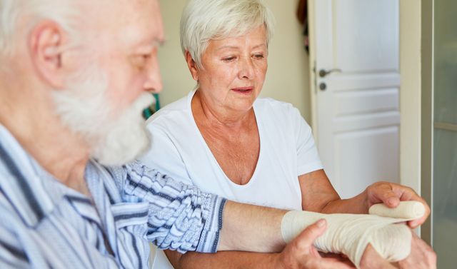 Eine Pflegekraft behandelt eine chronische Wunde bei einem älteren Patienten.