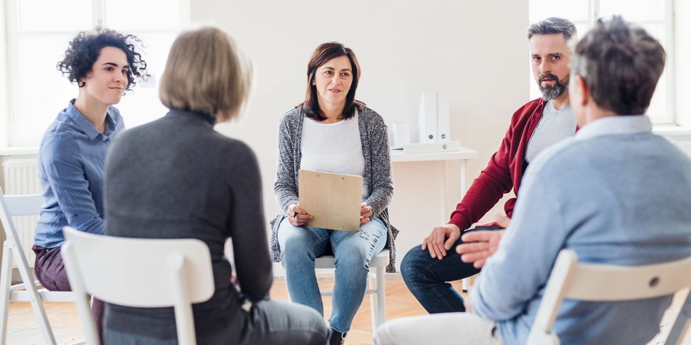 Man sieht eine Gruppe von Menschen, die zusammen an einer Gruppentherapie wegen ihrer Panikattacken teilnehmen.