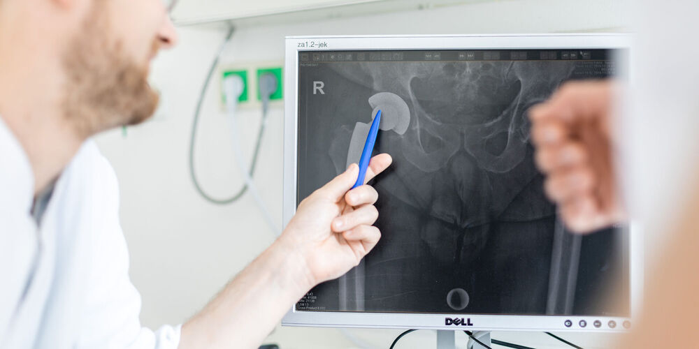 Das Bild zeigt einen Arzt bei der orthopädischen Untersuchung mit einem Patienten.