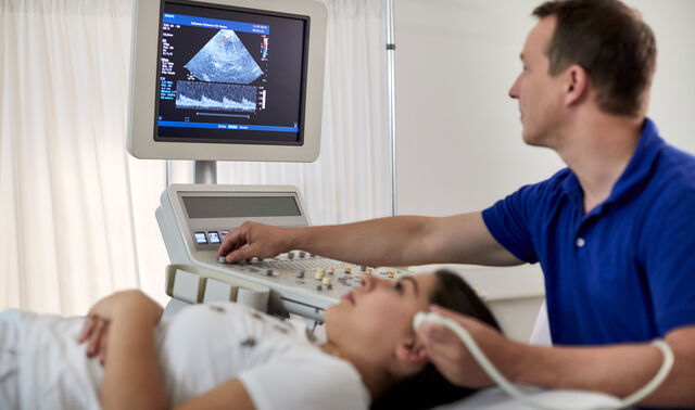 Ein Arzt der Neurologie im Johanna Etienne Krankenhaus führt einen Ultraschall an der Schläfe einer Patientin durch. 